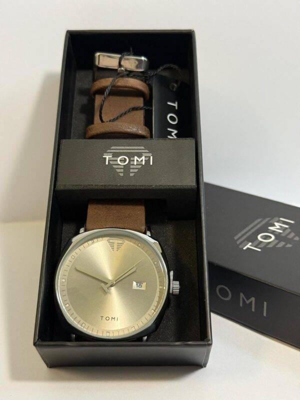 Side view of TOMI watch in packaging, highlighting brown leather strap and box design.